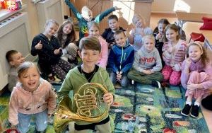 Tomek - uczeń klasy IV a z waltornią w ręku, na tle uśmiechniętych dzieci z klasy Id