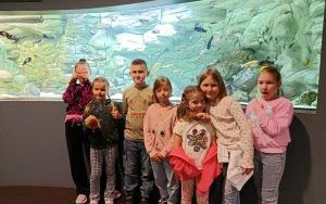 Uczniowie klasy 1d pozujący na tle akwarium z małymi rybami 