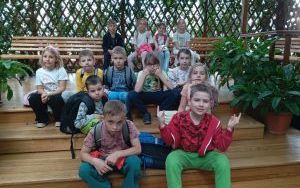 Uczniowie pozują do zdjęcia na schodach i ławkach
