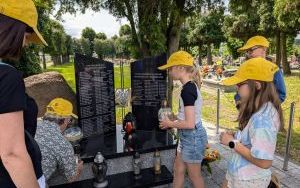 Uczniowie zapalają znicz na cmentarzu w Palowicach